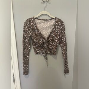 small brown long sleeve crop top with white pink and grey flowers all over it